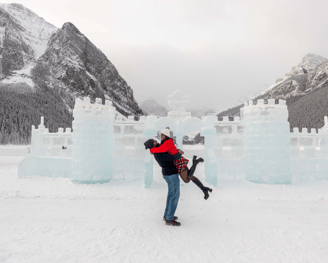 a man and woman in front of the lake louise ice castle 