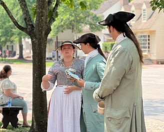 Colonial villagers in Williamsburg stood in the street chatting.