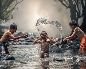 three boys playing in a stream of water