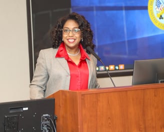 Rosalyn Cousins a woman in a suit and glasses standing at a podium