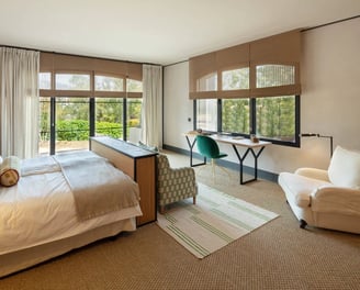 Bright bedroom suite at Villa La Gratitud with garden views, cozy seating, and soft natural tones.