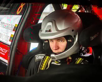 focused codriver with a helmet siting in a rally car and preparing for a stage start