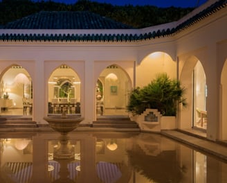 Courtyard at Villa El Rincon featuring a central fountain surrounded by flooded reflective flooring and classic arches.