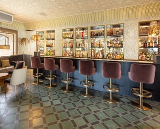 Chic cocktail bar at Villa La Gratitud, featuring plush seating, vintage decor, and a mirrored back.