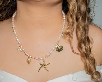 a woman wearing a white dress and a necklace with a starfish