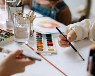 a child's hands holding a paintbrush and a paintbrush