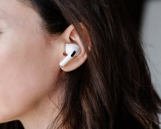 Profile of a women with long, dark hair, with air pods in her ears.