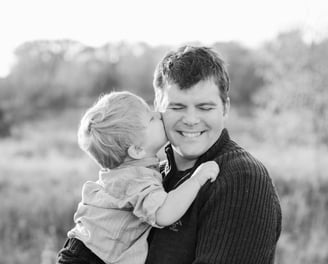 little boy kissing father on the cheek. Black and white image.