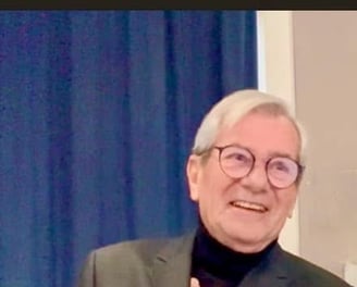 a man in a suit and glasses smiling