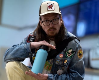 Portrait of a fashionably dressed man holding a blue water bottle