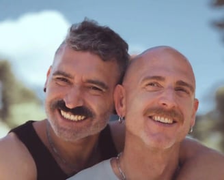 Dos hombres enamorados se abrazan felices frente a la cámara en una sesión fotográfica romántica LGBTQ+