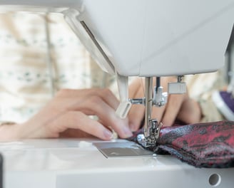 Gros plan sur des mains guidant le tissus sur une machine à coudre