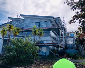 a man in a green shirt standing in front of a house