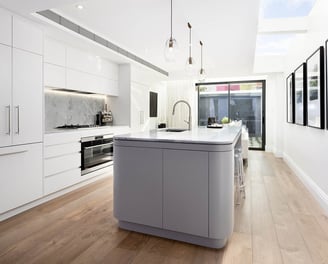 Central kitchen island with quartz countertop, integrated sink, casual dining space, skylights