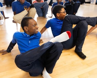 Students do a leg stretch together.