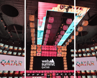 A vibrant stage setup at Web Summit Qatar with colorful LED displays and intricate lighting design.