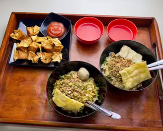 Tray berisi dua mangkuk mie ayam dengan topping lengkap, dua mangkuk saus, dan pangsit goreng