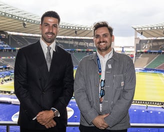 Sami Khedira (ex German footballer) and Tim Dougill posing for a photo in front of Berlin Stadium.
