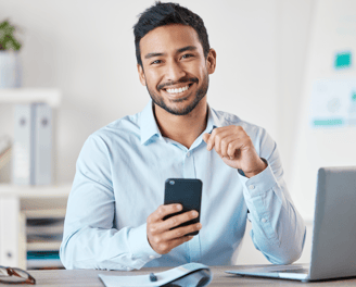a man sitting at a desk with a cell phone in his hand