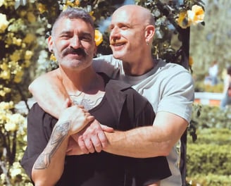 Pareja gay de hombres abrazándose y sonriendo durante una sesión de fotos de boda al aire libre en España