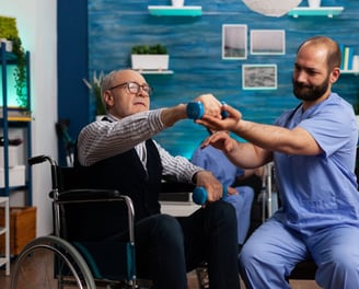 Un hombre ayudando a una persona de mayor edad con ejercicios de movilidad