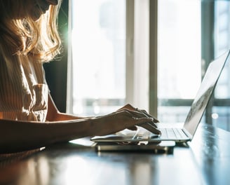A woman with long blonde hair working on a laptop.