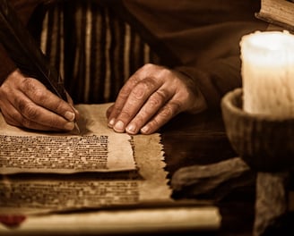 a man is writing a book on a table by a candle