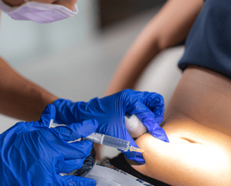 a woman in a blue dress is getting a tattoo on her belly