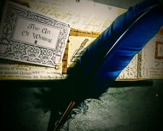 A blue feathered quill on a dark background - The Art Of Writing