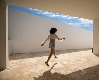 a woman in a white shirt and skirt jumping on a tiled floor in an architect house