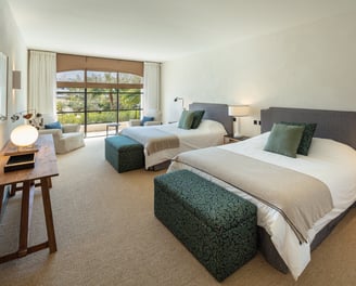 Spacious guest bedroom at Villa La Gratitud with two large beds, garden views, and cozy seating area