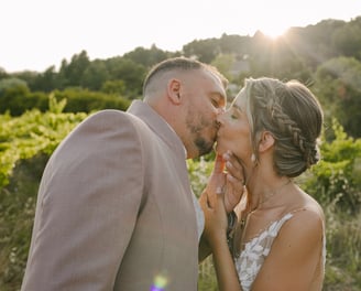un couple jeune marié qui s'embrasse au coucher du soleil au milieu des vignes