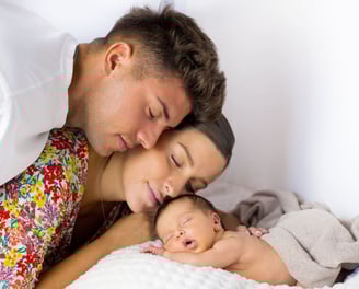 Sessió de fotos newborn a Girona amb bebè recent nascuda dormint amb els pares en estudi fotogràfic