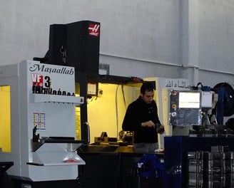 a man in a black shirt is standing in a machine shop