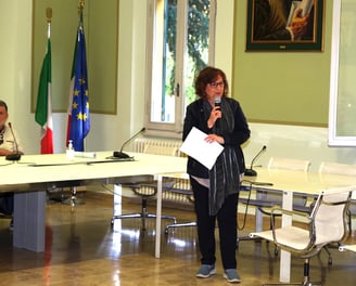 a woman standing in front of a table with a microphone