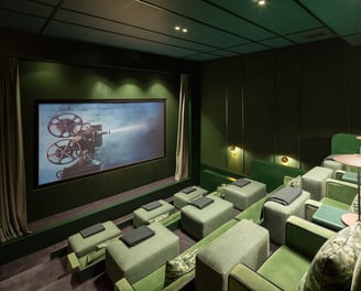 Private cinema at Villa La Gratitud with plush green seats, designer lighting, and big screen.