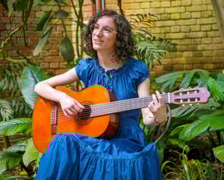 chanteuse guitariste en robe bleue chantant dans une serre