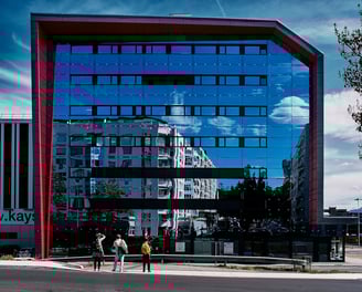 a person walking down a street with a large mirrored building in the background, in Geneva
