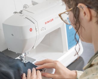 Vu de dos d'une personne cousant sur une machine à coudre