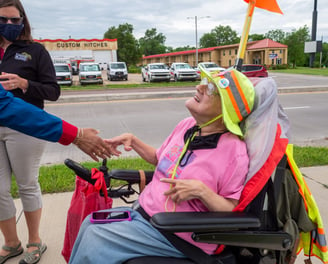 Photo of Dawn Zuterberg sitting in her electronic scooter, shaking someone's hand