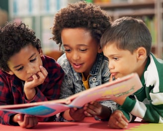 three children are reading a book together in Reno preschool school readiness program