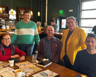 Group of smiling men and women at a table in a coffee house