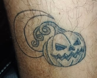 a tattoo on a man's leg with a pumpkin