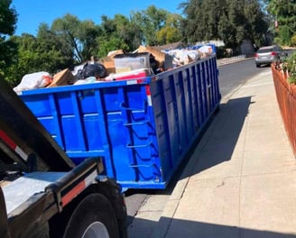 a dumpster truck with a large amount of trash in the back of it