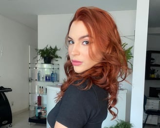 Mulher ruiva, cabelos ondulados com olhar profundo.
