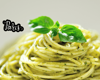 a bowl of pasta with pesto and basil leaves