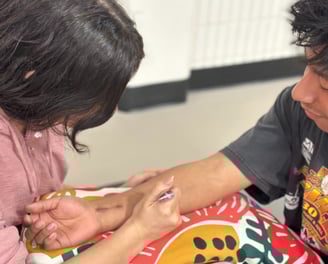 young woman applying henna to forearm of smiling young man