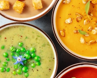 a variety of vegan soups in bowls with a variety of toppings
