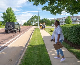 Full-body shot of Sophia Smith walking down a sidewalk with a clipboard in hand