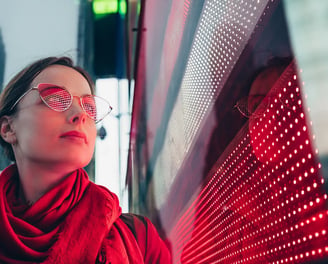 a woman in a red scarf and glasses next to led screen